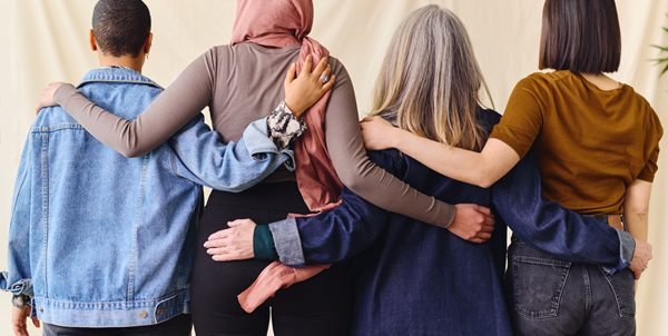 Four women standing arm in arm